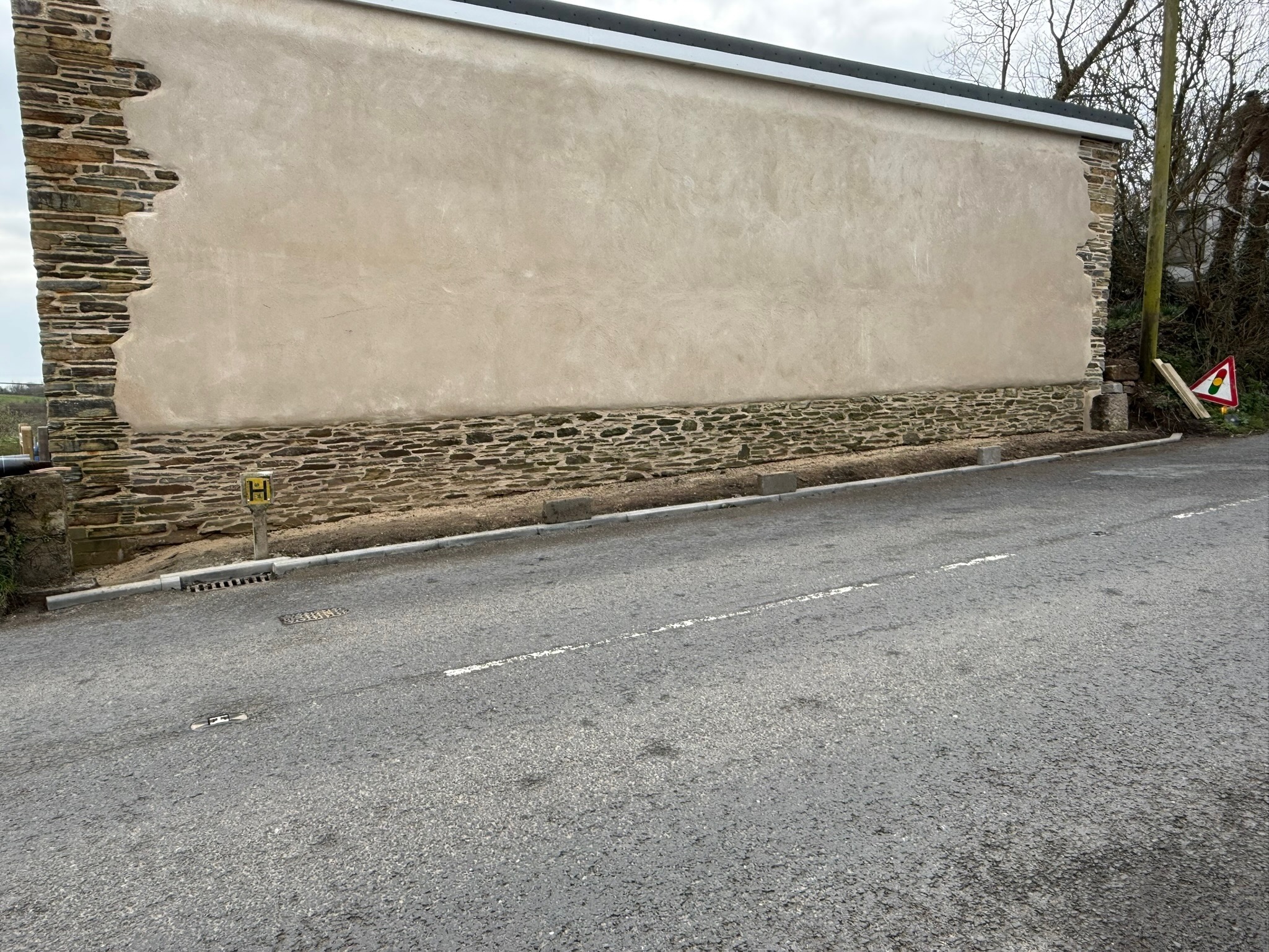 Completed heritage cob wall with natural lime render finish and natural stone corners on a former Cornish post office