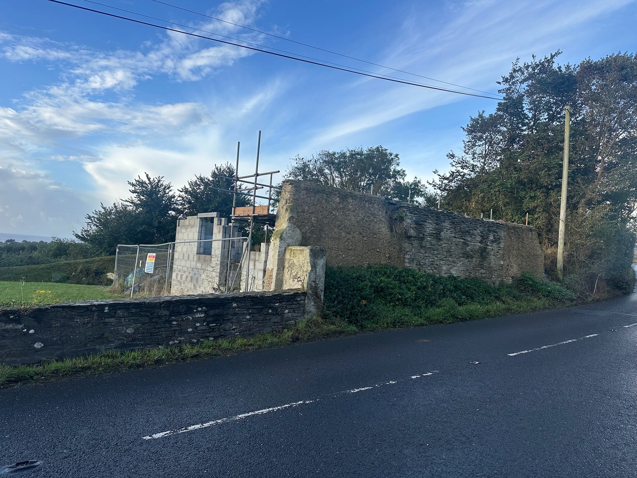 Original heritage farm building with the deteriorating roadside cob wall and early scaffold setup