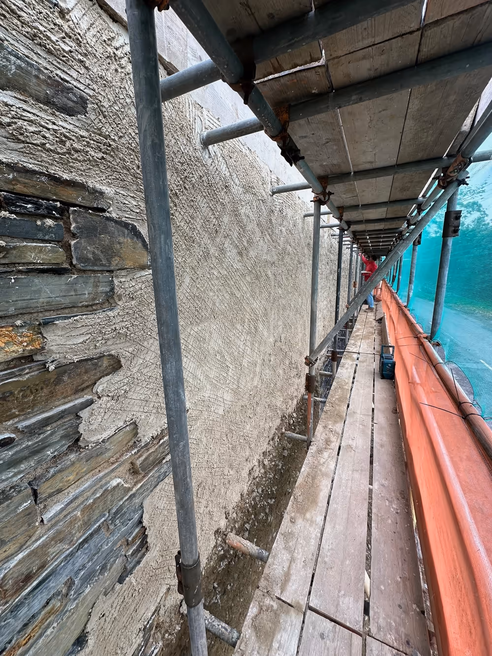 The first coat of natural lime render going on alongside the existing cob